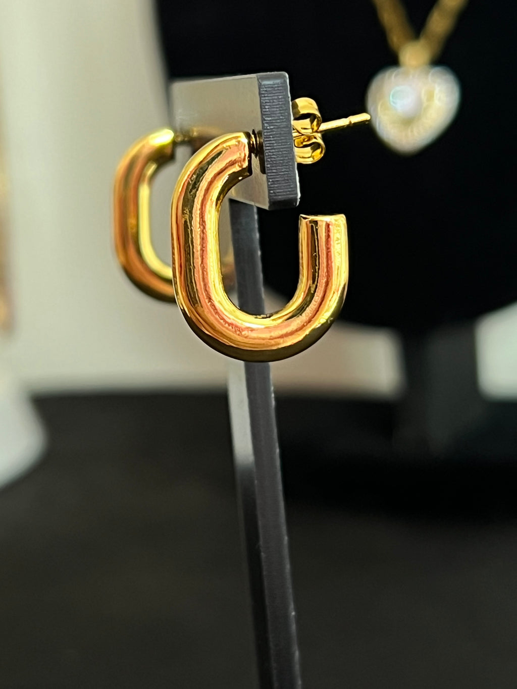 Gold chunky oval hoop earrings on black jewellery stand