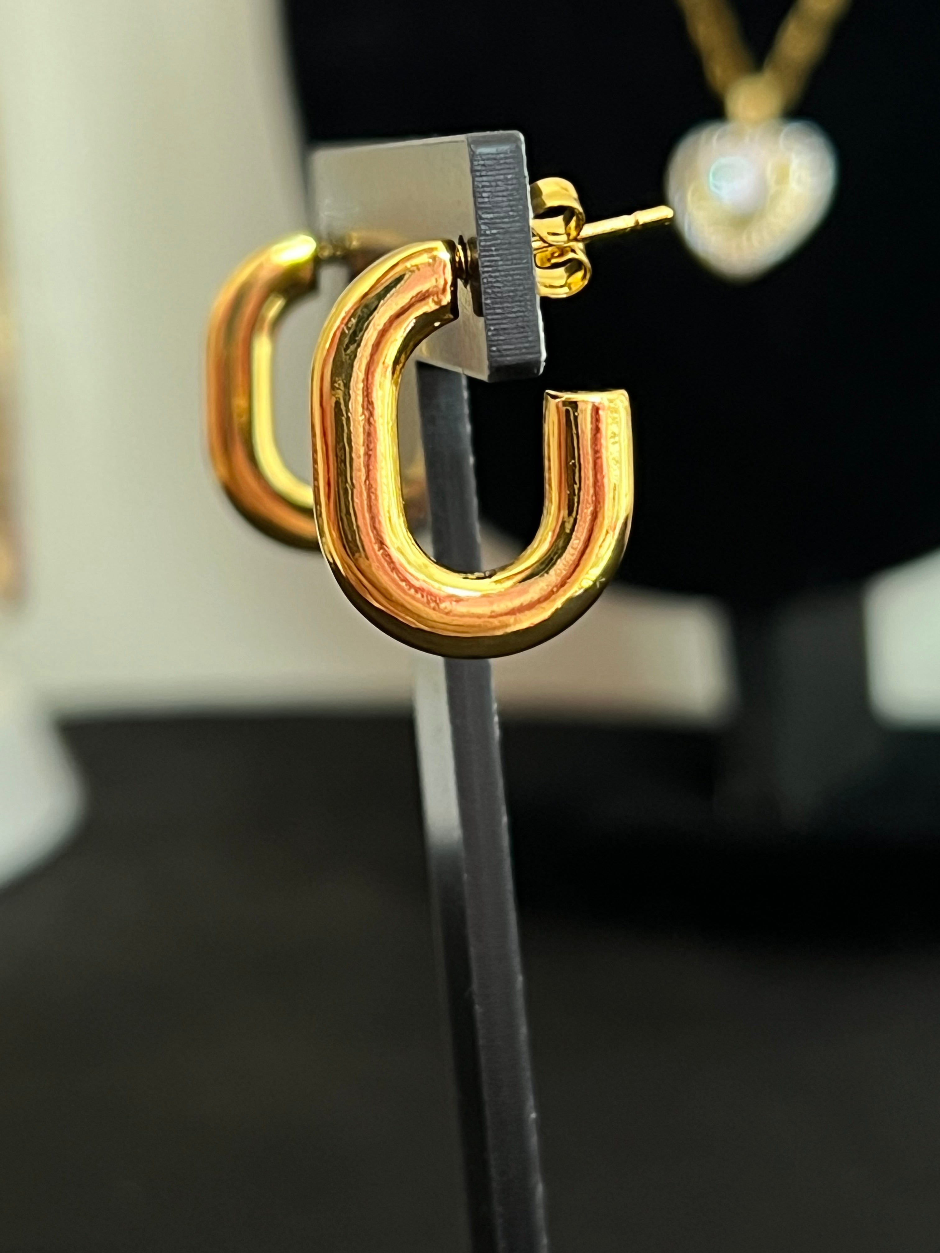 Gold chunky oval hoop earrings on black jewellery stand