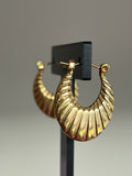 Gold ribbed crescent hoop earrings on black jewellery stand