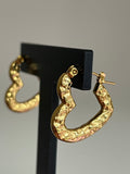 Gold hammered heart hoop earrings on black jewellery stand