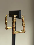 Gold bamboo square hoop earrings on black jewellery stand