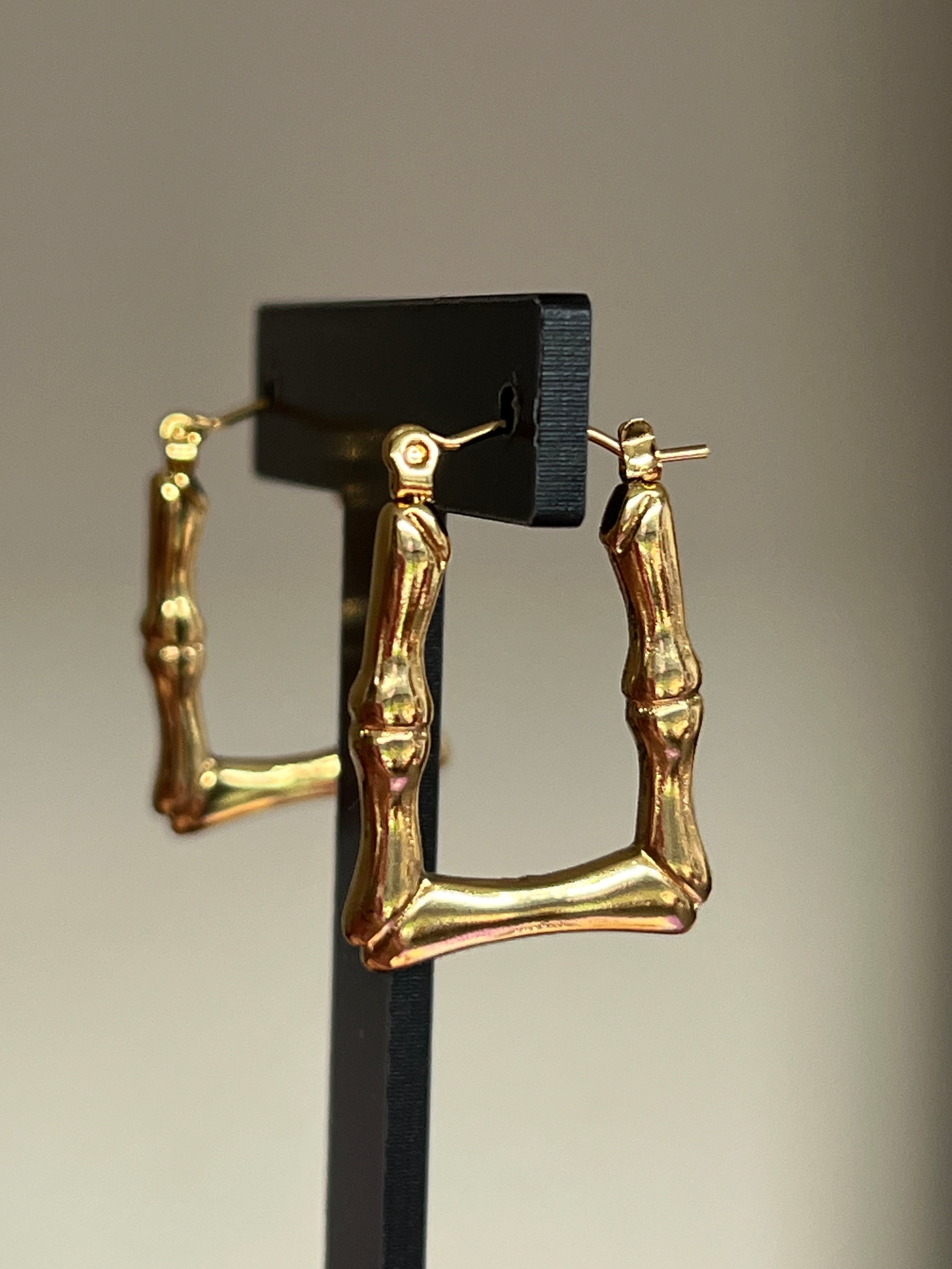 Gold bamboo square hoop earrings on black jewellery stand