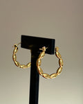 Gold beaded hoop earrings displayed on black jewellery stand