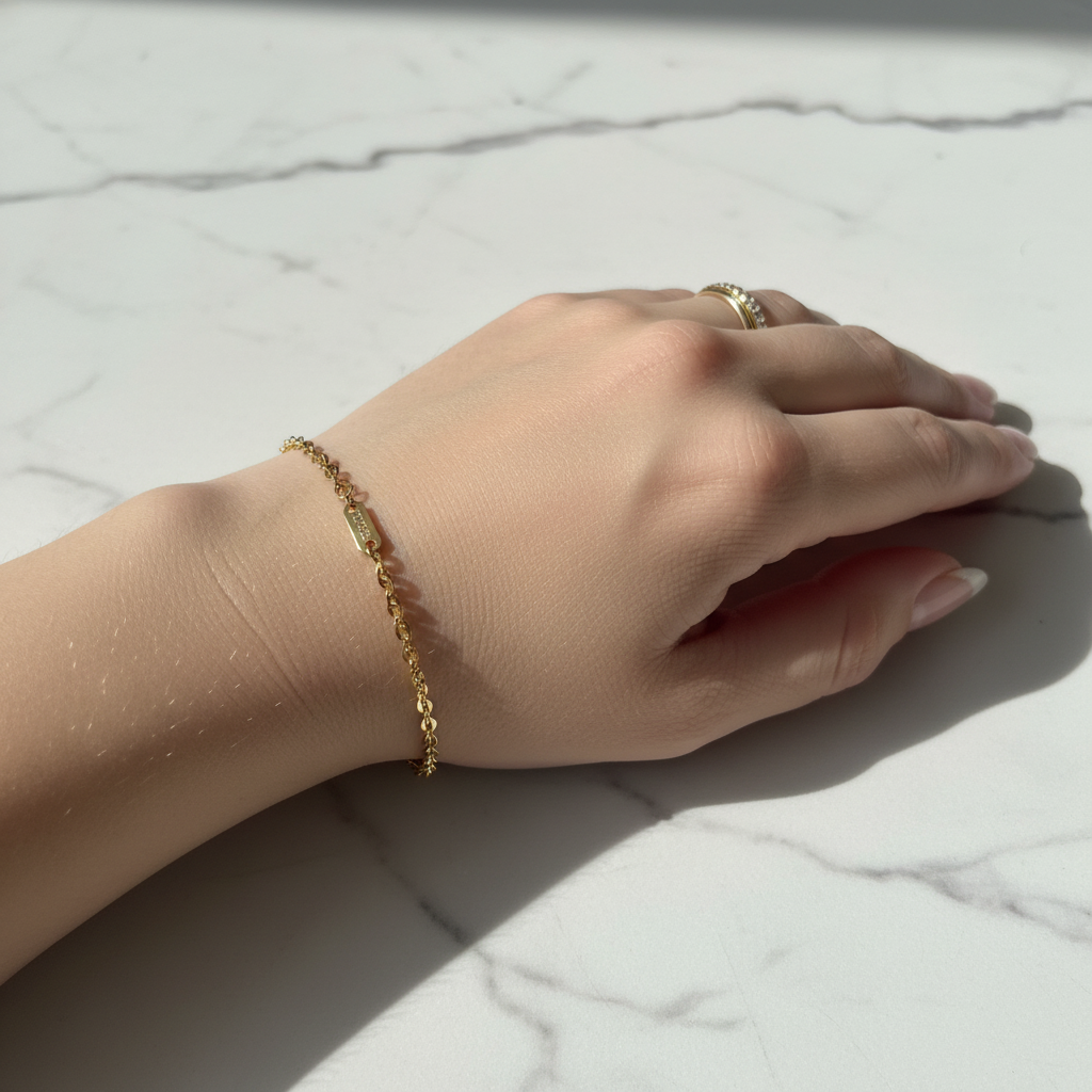 Gold oval cable chain bracelet worn on woman's wrist, lifestyle shot