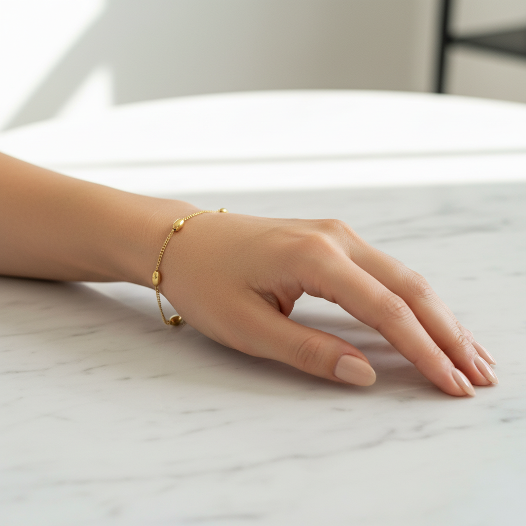 Gold bead station bracelet worn on woman's wrist, lifestyle shot