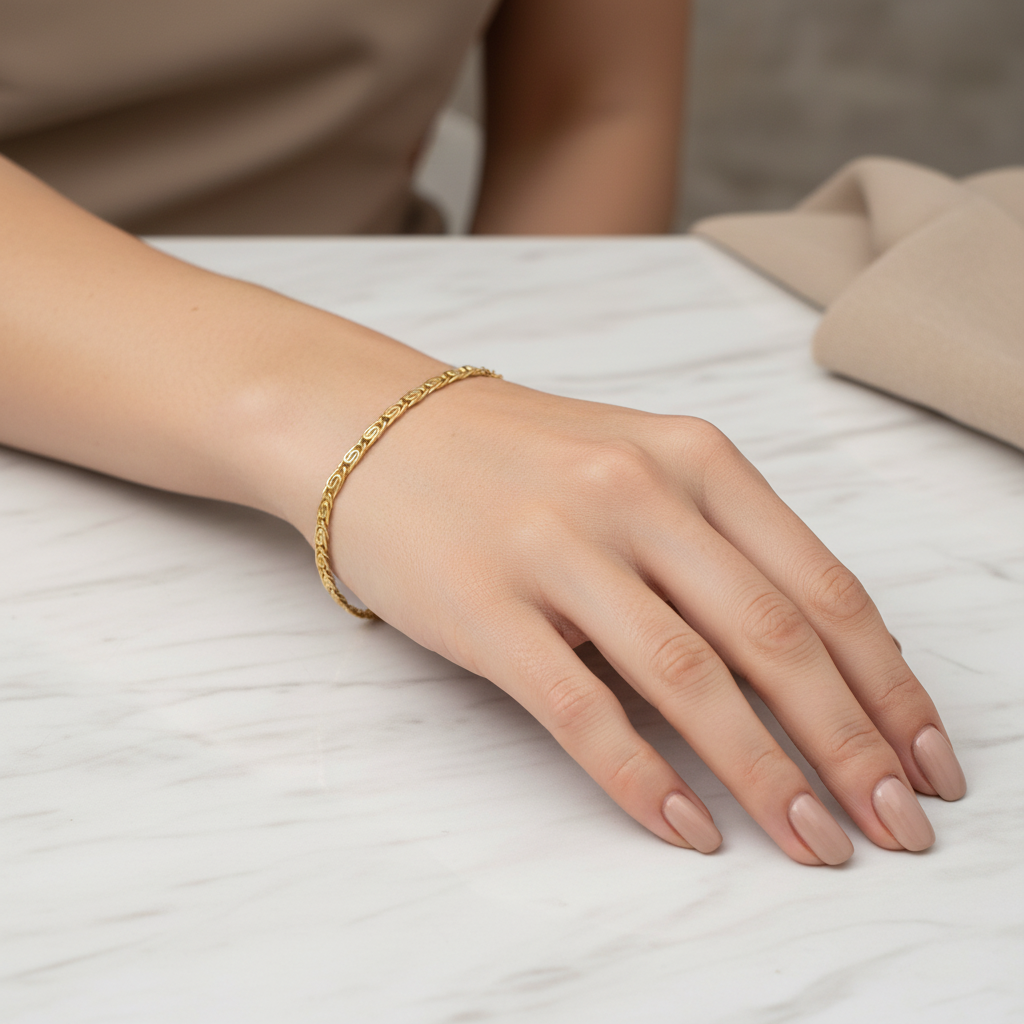 Gold Greek key chain bracelet worn on woman's wrist, lifestyle shot